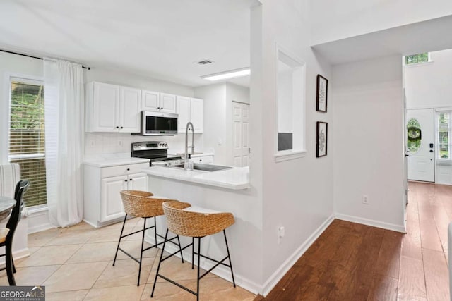 1825 Millstone Ct, Alpharetta, GA 30004 - kitchen featuring appliances with stainless steel finishes, light countertops, a kitchen breakfast bar, and healthy amount of natural light