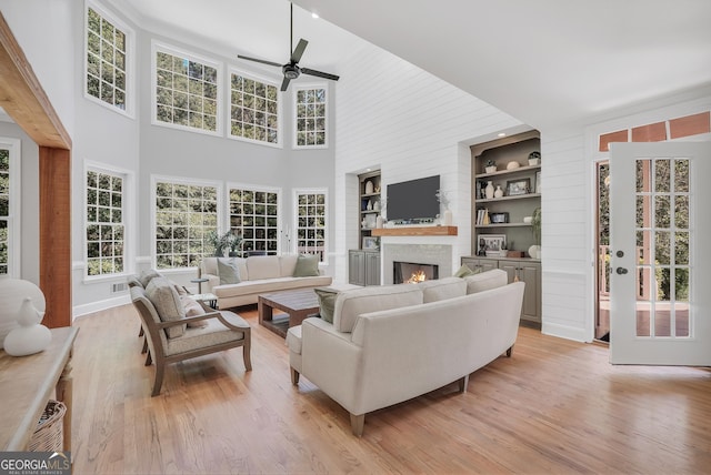 100 Castlebrook Chase, Tyrone, GA 30290 - living area featuring ceiling fan, light wood-type flooring, built in shelves, a warm lit fireplace, and plenty of natural light