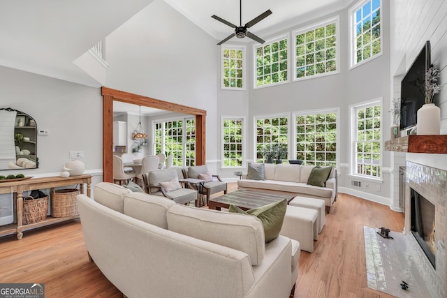 100 Castlebrook Chase, Tyrone, GA 30290 - living room featuring ceiling fan, a fireplace with flush hearth, light wood-type flooring, a towering ceiling, and crown molding
