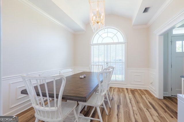 1112 Old Meadow Rd, Valdosta, GA 31605 - dining space with lofted ceiling, a chandelier, a wainscoted wall, a decorative wall, and light wood-style flooring