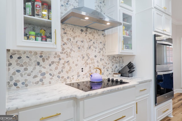 1112 Old Meadow Rd, Valdosta, GA 31605 - kitchen featuring wall chimney exhaust hood, black appliances, decorative backsplash, wood finished floors, and white cabinetry