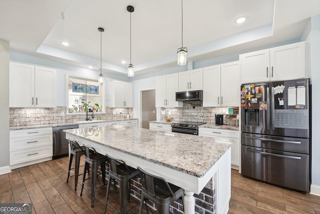 357 Old Driver Rd, Whitesburg, GA 30185 - kitchen with appliances with stainless steel finishes, a tray ceiling, a center island, dark wood-style flooring, and recessed lighting