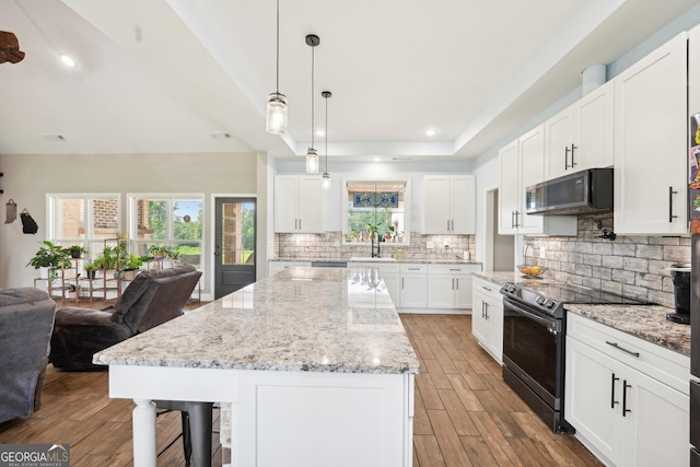 357 Old Driver Rd, Whitesburg, GA 30185 - kitchen with stainless steel appliances, wood finished floors, backsplash, a breakfast bar, and white cabinetry