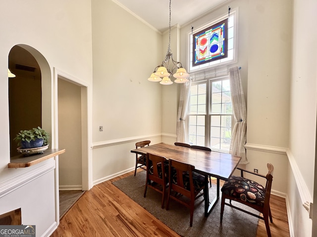 235 Pirkle Ct, Cumming, GA 30040 - dining room featuring a high ceiling, wood finished floors, a chandelier, ornamental molding, and arched walkways