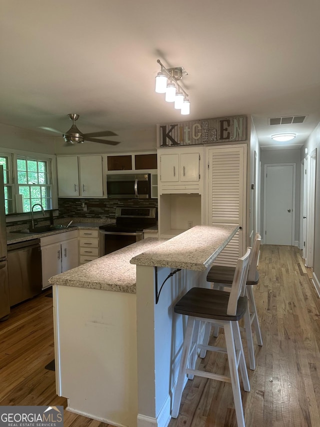 1408 Main St, Perry, GA 31069 - kitchen with appliances with stainless steel finishes, wood finished floors, a ceiling fan, white cabinets, and open shelves