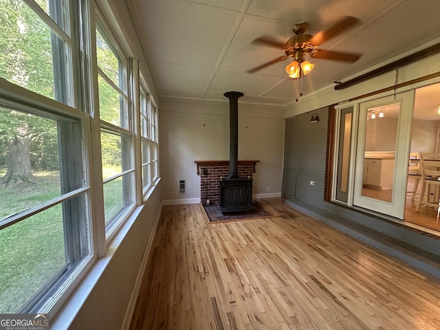 1408 Main St, Perry, GA 31069 - unfurnished living room with a wood stove, plenty of natural light, wood finished floors, ceiling fan, and crown molding