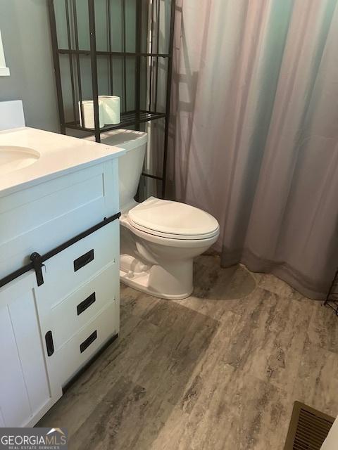 1408 Main St, Perry, GA 31069 - bathroom featuring vanity, wood finished floors, and a shower with shower curtain