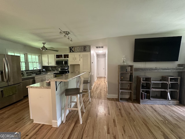 1408 Main St, Perry, GA 31069 - kitchen with appliances with stainless steel finishes, ceiling fan, wood finished floors, white cabinetry, and backsplash
