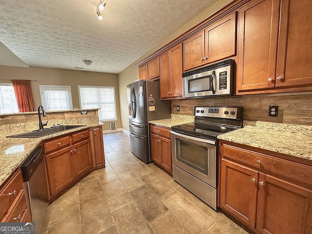 101 Riverchest Dr, Lagrange, GA 30240 - kitchen featuring stainless steel appliances, tasteful backsplash, plenty of natural light, brown cabinetry, and a textured ceiling