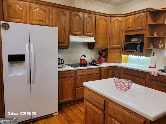1904 S State Line Rd, Lagrange, GA 30240 - kitchen featuring white fridge with ice dispenser, stainless steel microwave, black electric cooktop, under cabinet range hood, and ornamental molding