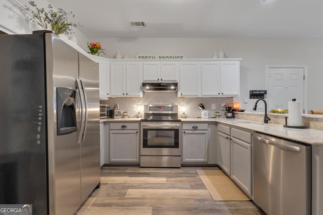259 Coweta St, Senoia, GA 30276 - kitchen with stainless steel appliances, under cabinet range hood, light wood-style floors, light countertops, and a peninsula