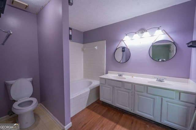 7472 Woods Ct, Lithonia, GA 30058 - bathroom featuring double vanity, a textured ceiling, wood finished floors, and tiled shower / bath