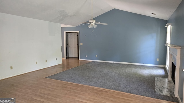 1448 SE Hillside Pl, Conyers, GA 30094 - unfurnished living room featuring a ceiling fan, vaulted ceiling, a fireplace, and wood finished floors