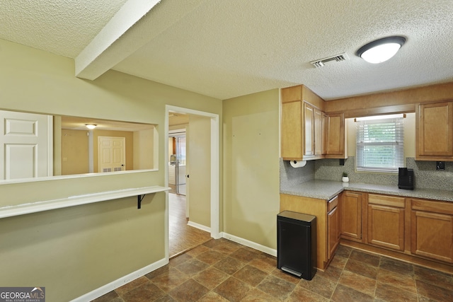 233 S Sheffield St, Kingsland, GA 31548 - kitchen featuring a textured ceiling, decorative backsplash, dark stone finish floors, brown cabinetry, and light countertops