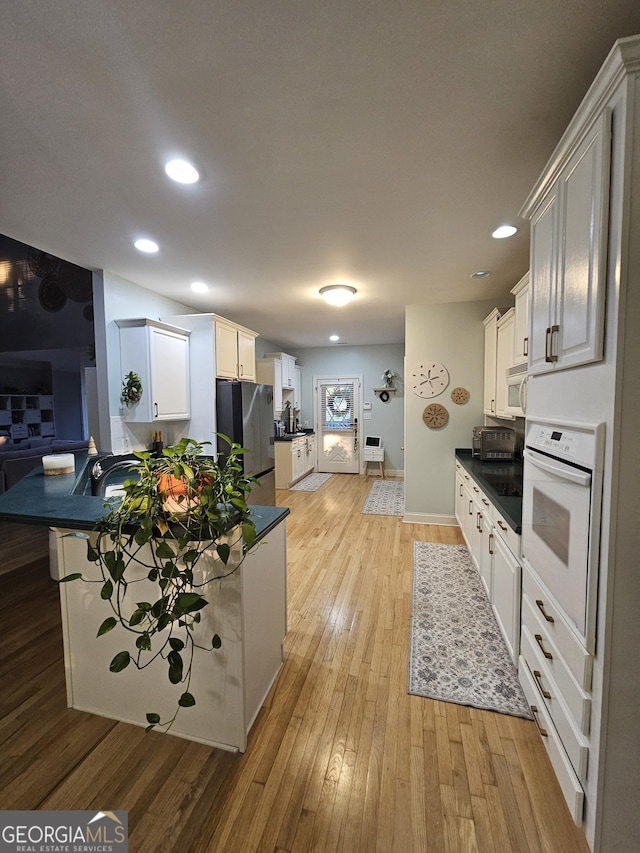 200 Chaparral Trce, Tyrone, GA 30290 - kitchen with white appliances, light wood finished floors, dark countertops, recessed lighting, and white cabinets
