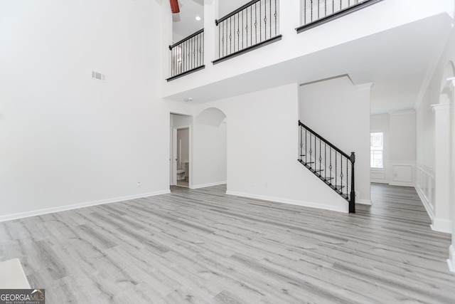 2023 Jameson Cir, Lawrenceville, GA 30043 - unfurnished living room with stairway, wood finished floors, arched walkways, ornamental molding, and a high ceiling