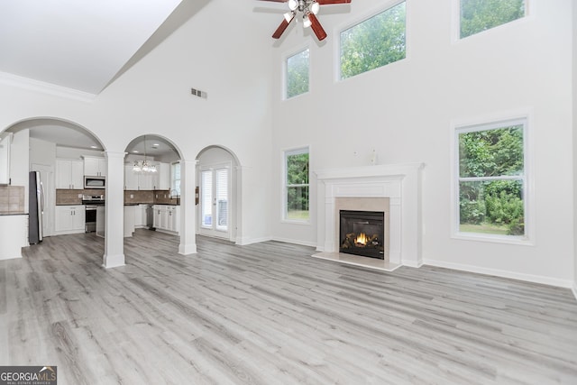 2023 Jameson Cir, Lawrenceville, GA 30043 - unfurnished living room with ceiling fan, a premium fireplace, a towering ceiling, ornamental molding, and arched walkways