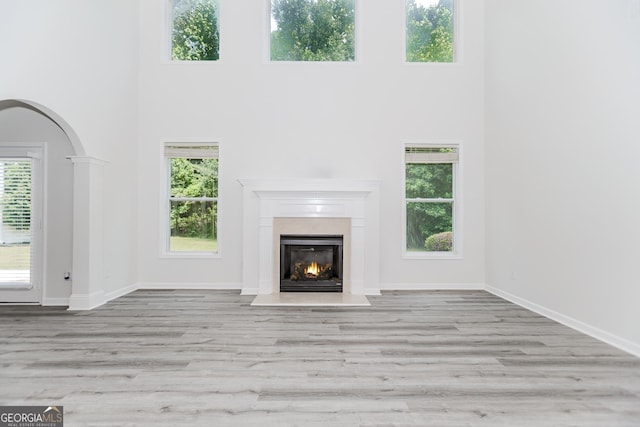 2023 Jameson Cir, Lawrenceville, GA 30043 - unfurnished living room with a towering ceiling, a fireplace with flush hearth, wood finished floors, and arched walkways
