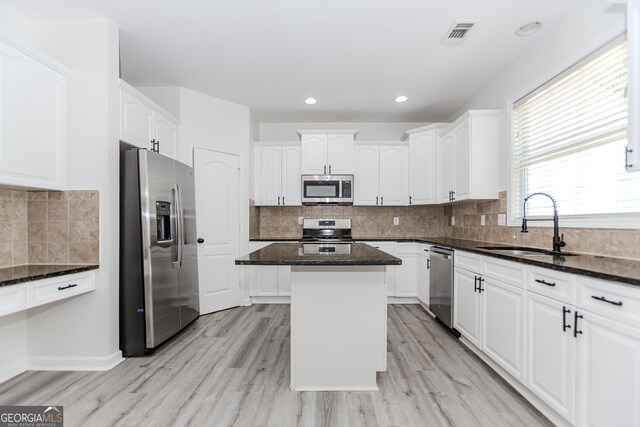 2023 Jameson Cir, Lawrenceville, GA 30043 - kitchen with stainless steel appliances, a kitchen island, dark stone countertops, white cabinetry, and light wood-type flooring