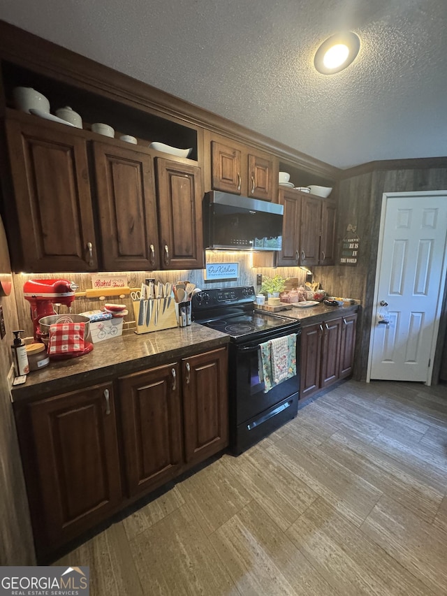 92 Graham Ln, Claxton, GA 30417 - kitchen featuring black range with electric cooktop, stainless steel microwave, a textured ceiling, dark brown cabinetry, and light wood-type flooring