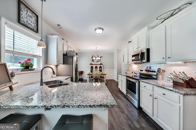 93 Oakdale Way, Temple, GA 30179 - kitchen featuring appliances with stainless steel finishes, white cabinets, a peninsula, light stone countertops, and ornamental molding