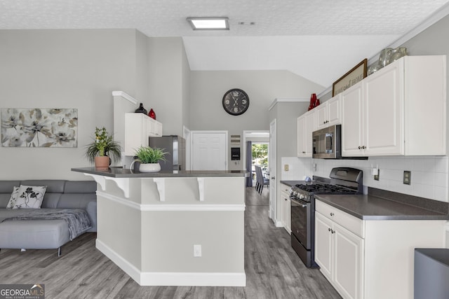 499 Running Doe Ct, Suwanee, GA 30024 - kitchen featuring stainless steel appliances, dark countertops, light wood finished floors, white cabinets, and backsplash