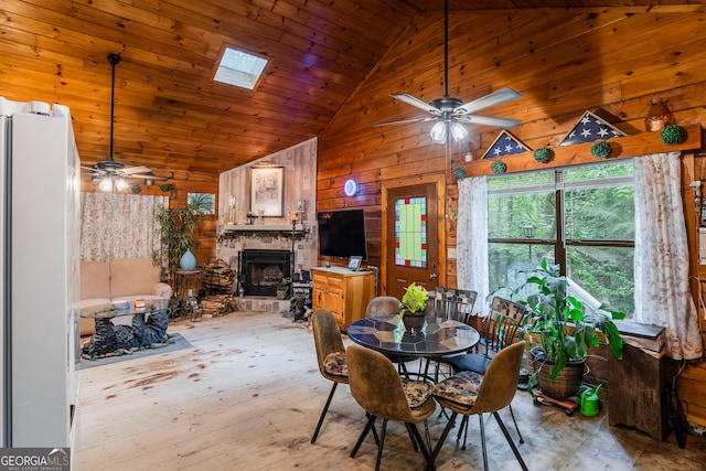 12 Scott Dr, Ellijay, GA 30540 - dining room featuring a ceiling fan, wooden walls, a stone fireplace, high vaulted ceiling, and a skylight