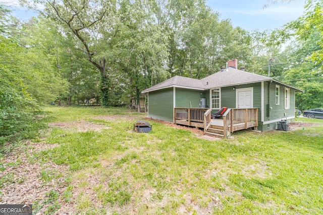 116 6th St, Monroe, GA 30655 - rear view of house featuring a chimney, a wooden deck, a lawn, a fire pit, and roof with shingles
