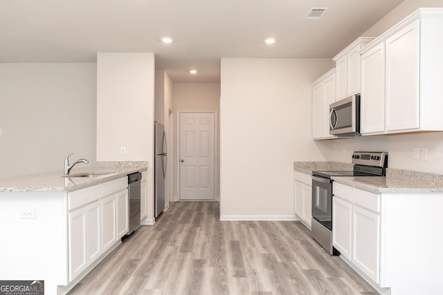 102 Avondale Blvd, Conyers, GA 30013 - kitchen featuring appliances with stainless steel finishes, a peninsula, light wood-type flooring, recessed lighting, and light stone countertops