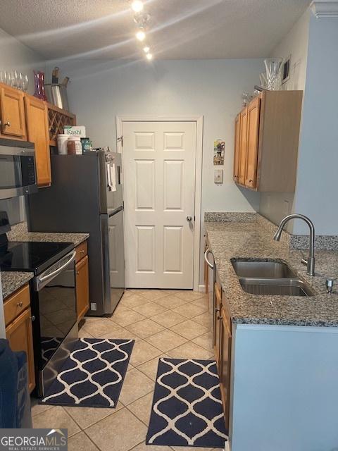 4333 Dunwoody Park Unit 2214, Atlanta, GA 30338 - kitchen with appliances with stainless steel finishes, light tile patterned flooring, dark stone counters, brown cabinetry, and a textured ceiling