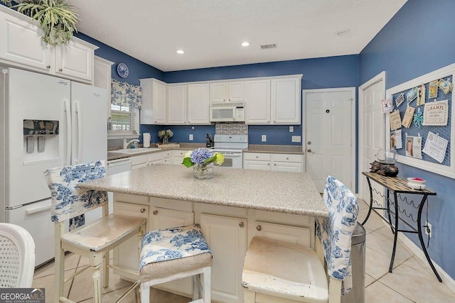 21 Hardwood Forest Cir, Brunswick, GA 31525 - kitchen with white appliances, white cabinets, a center island, light tile patterned floors, and recessed lighting