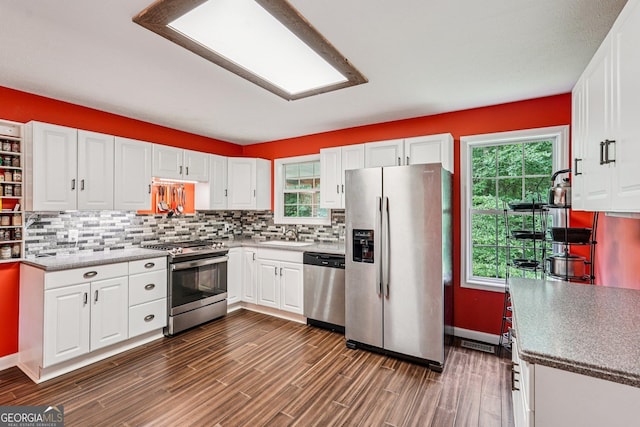 150 Buck Run E, Dahlonega, GA 30533 - kitchen featuring appliances with stainless steel finishes, dark wood-type flooring, white cabinetry, decorative backsplash, and plenty of natural light