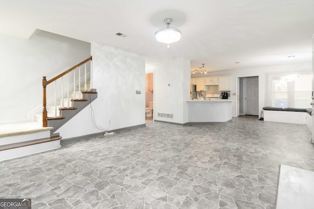 539 Riverbirch Trce, Stone Mountain, GA 30087 - unfurnished living room with stone flooring, stairway, and a chandelier