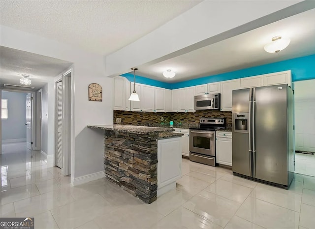 2917 W Clifton St, Tampa, FL 33614 - kitchen with stainless steel appliances, a peninsula, decorative backsplash, white cabinets, and pendant lighting