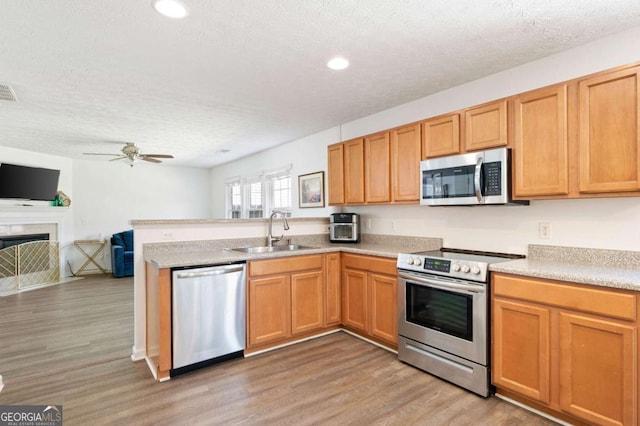 245 Weatherstone Pointe Dr, Woodstock, GA 30188 - kitchen with appliances with stainless steel finishes, a peninsula, light wood-style floors, open floor plan, and recessed lighting