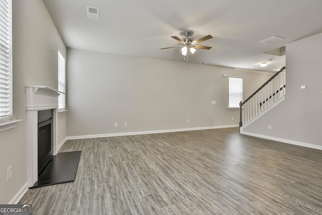 209 Merritt Cir, Newnan, GA 30263 - unfurnished living room with wood finished floors, ceiling fan, stairway, and a glass covered fireplace