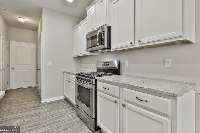 209 Merritt Cir, Newnan, GA 30263 - kitchen featuring stainless steel appliances, light wood-type flooring, white cabinetry, and light stone countertops