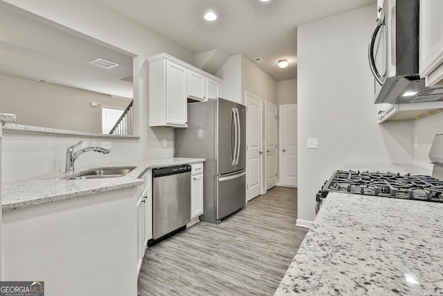 209 Merritt Cir, Newnan, GA 30263 - kitchen with appliances with stainless steel finishes, white cabinets, light wood finished floors, light stone counters, and recessed lighting
