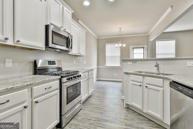 209 Merritt Cir, Newnan, GA 30263 - kitchen with appliances with stainless steel finishes, ornamental molding, white cabinets, light wood-type flooring, and decorative light fixtures