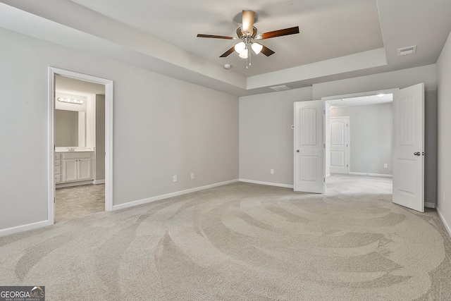 209 Merritt Cir, Newnan, GA 30263 - unfurnished bedroom featuring a tray ceiling, light colored carpet, and connected bathroom