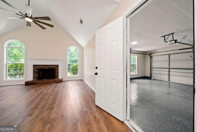 20 Four Oaks, Newnan, GA 30263 - unfurnished living room featuring a ceiling fan, plenty of natural light, a textured ceiling, lofted ceiling, and a stone fireplace