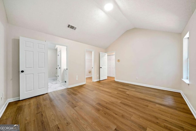 20 Four Oaks, Newnan, GA 30263 - unfurnished bedroom featuring vaulted ceiling, ensuite bath, and wood finished floors