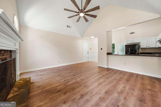 20 Four Oaks, Newnan, GA 30263 - unfurnished living room featuring high vaulted ceiling, a ceiling fan, a fireplace with raised hearth, and light wood-style flooring