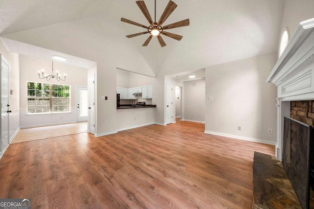 20 Four Oaks, Newnan, GA 30263 - unfurnished living room with a ceiling fan, a chandelier, light wood-type flooring, a fireplace, and high vaulted ceiling