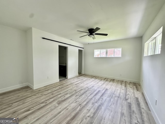 210 W Graham St, Mcrae-Helena, GA 31055 - unfurnished bedroom featuring a barn door, light wood-style floors, a ceiling fan, and a closet