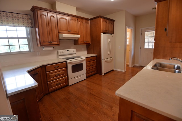 195 Twin Oaks Dr, Hampton, GA 30228 - kitchen with white appliances, under cabinet range hood, brown cabinets, and healthy amount of natural light
