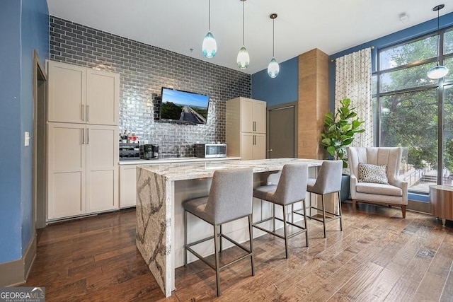 795 Hammond Dr Unit 1012, Atlanta, GA 30328 - kitchen with stainless steel microwave, dark wood-type flooring, light stone countertops, hanging light fixtures, and a kitchen bar