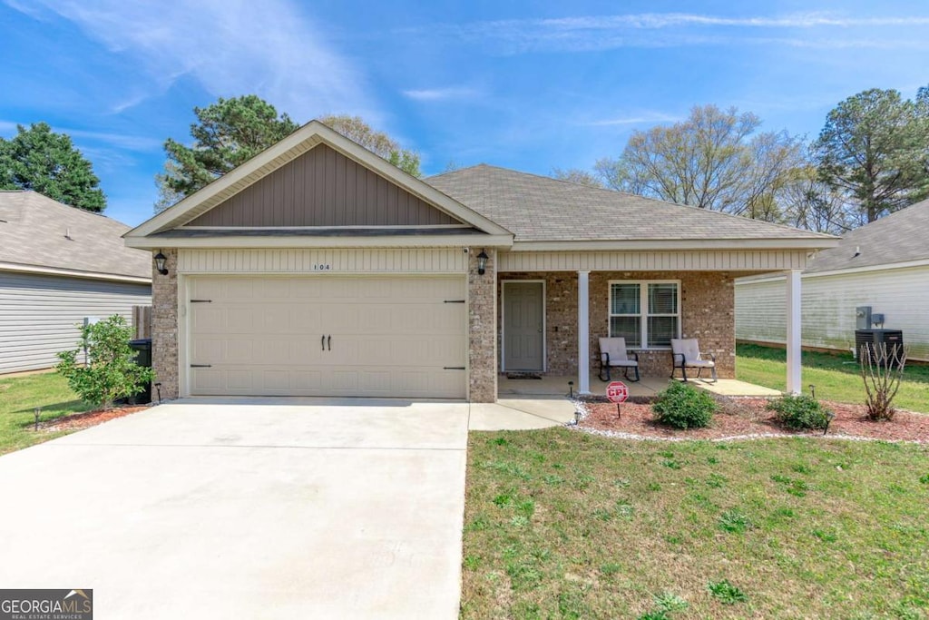 104 Hughes Dr, Warner Robins, GA 31093 - ranch-style house with covered porch, brick siding, a garage, a front lawn, and driveway