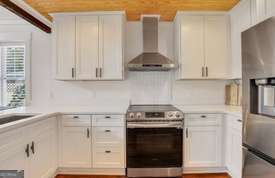 1016 Seiler Ave, Savannah, GA 31401 - kitchen with wall chimney exhaust hood, stainless steel appliances, light countertops, and white cabinetry