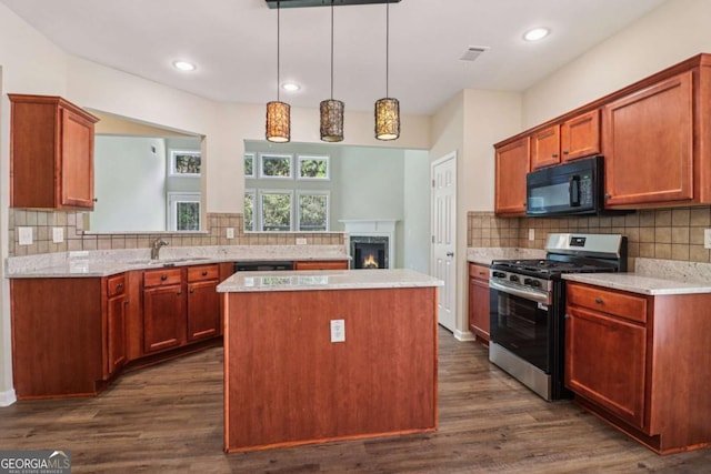 1755 Rutland Pass Dr, Lawrenceville, GA 30045 - kitchen with gas range, black microwave, a kitchen island, a lit fireplace, and decorative backsplash